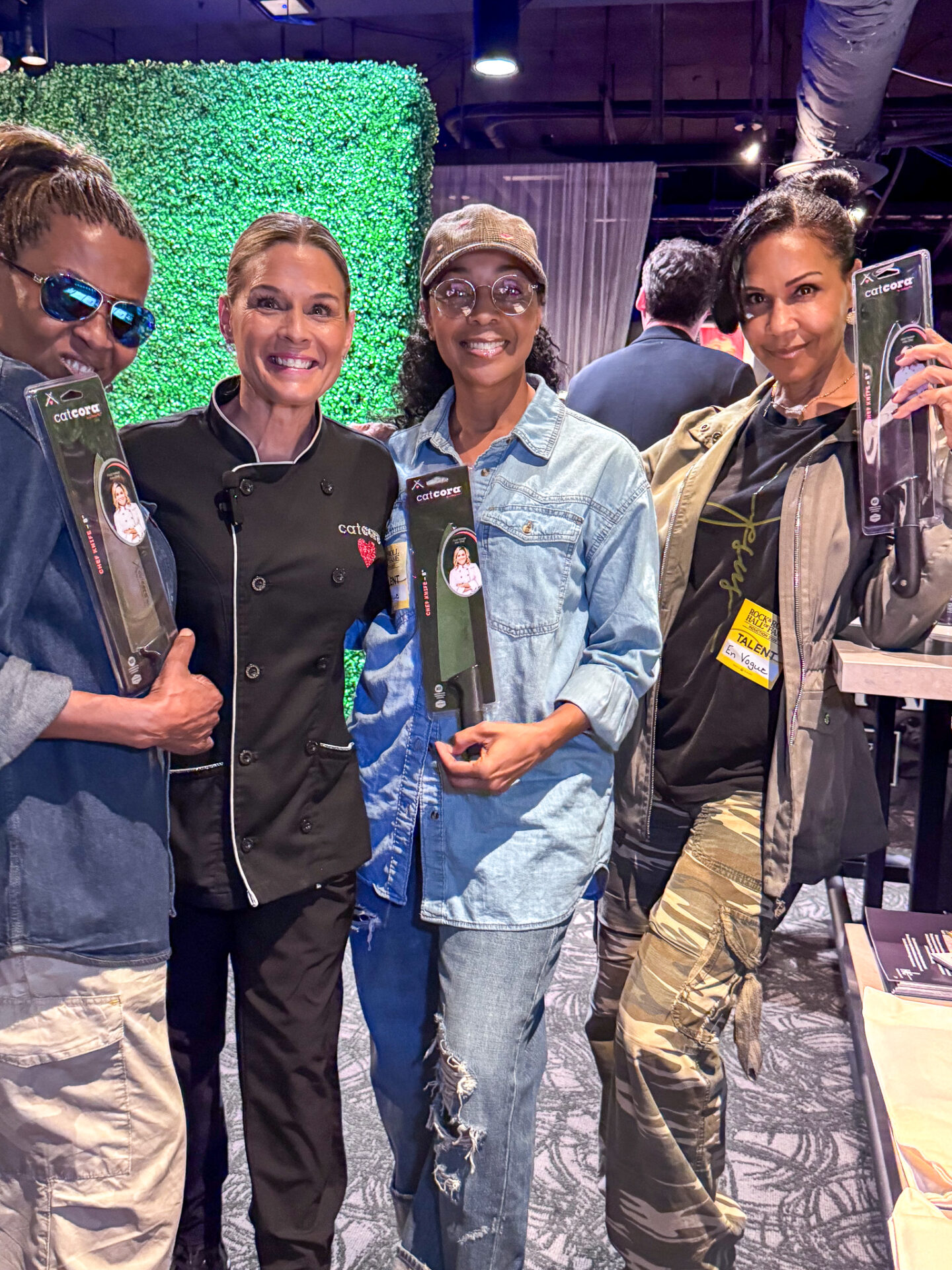 Celebrity Chef Cat Cora Posing with Terry Ellis, Maxine Jones, and Cindy Herron, holding Cat Cora Kitchen Essentials