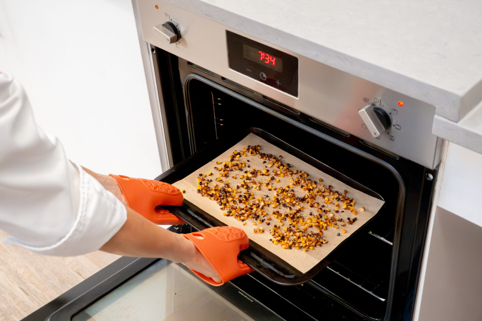Placing the corn kernels in the oven to roast. 